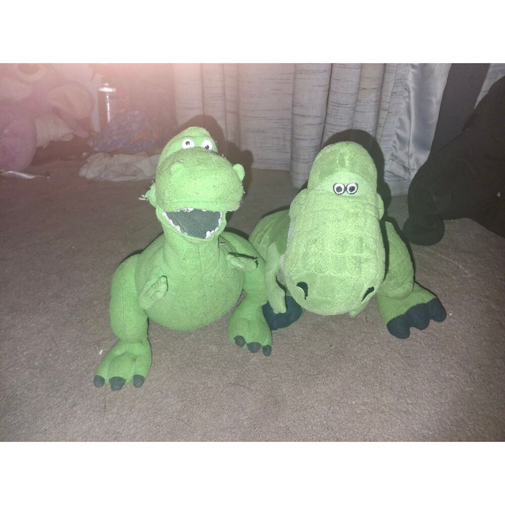Two green dinosaur stuffed animals, one with mouth open